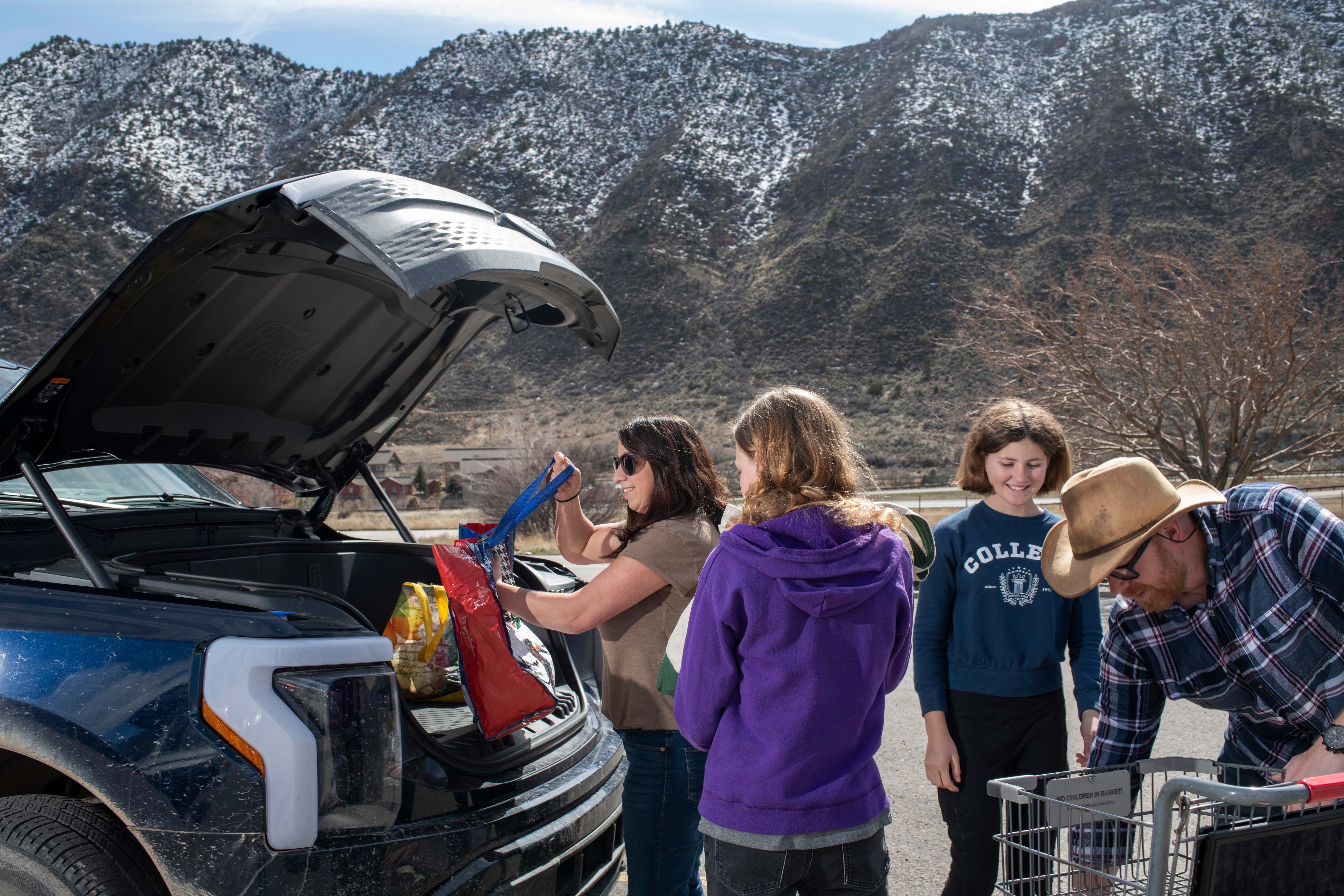 From left, Amy Westby, her daughters, Lizzie Westby, 13, and Ari Westby, 12, help unload groceries next to their father and AmyÕs husband, Ben Westby, into the frunk of their Ford F-150 Lightning on Sunday, March 17, 2024 in New Castle, Colorado. Rachel Woolf for Ford